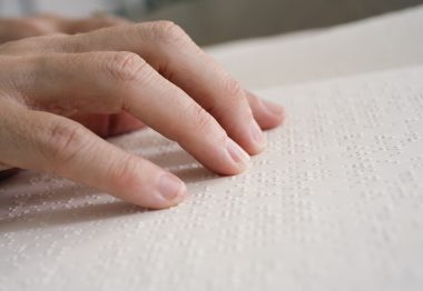 Des doigts parcourent une page en braille