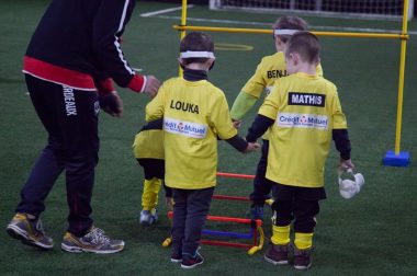 Les enfants joueurs de foot se déplacent lors d'une sensibilisation au cécifoot
