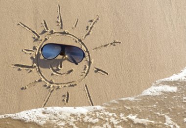 Soleil déssiné sur le sable avec lunettes à la place des yeux.